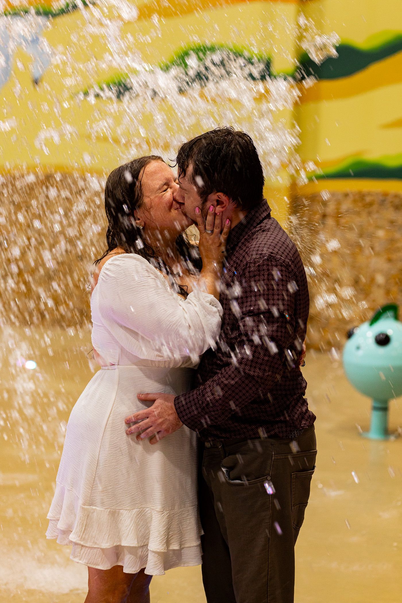 Couple kissing during engagement session a while at a splash park