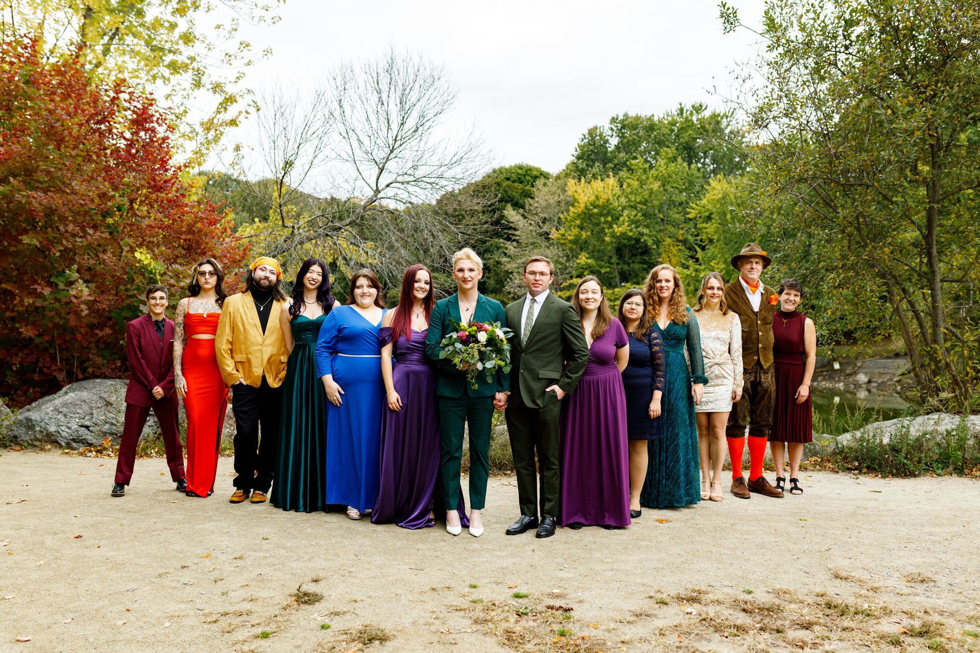 Gay couple posing with their wedding party in rainbow outfits