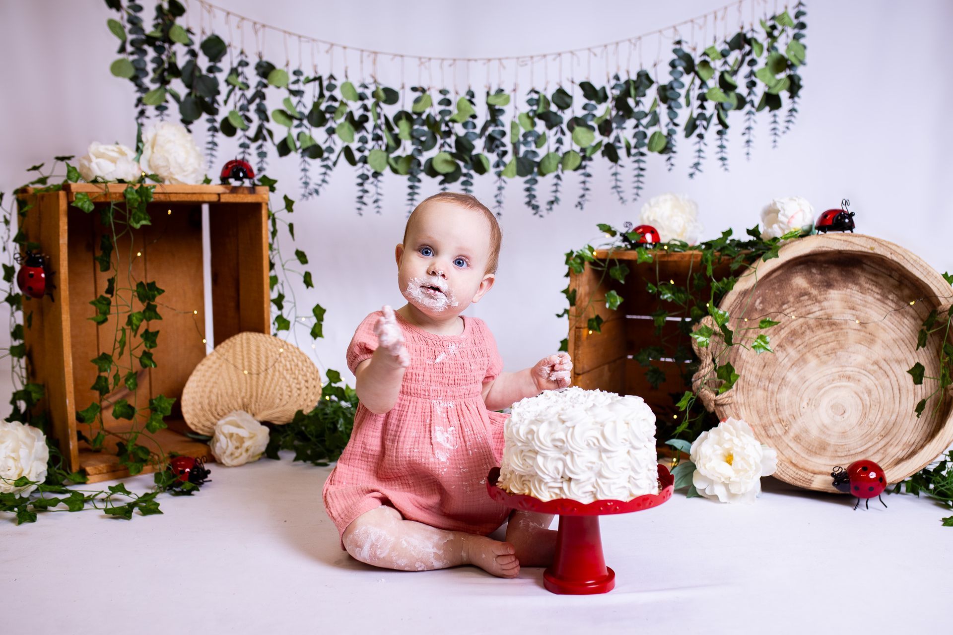 Baby posing on white background for ladybug themed cake smash session