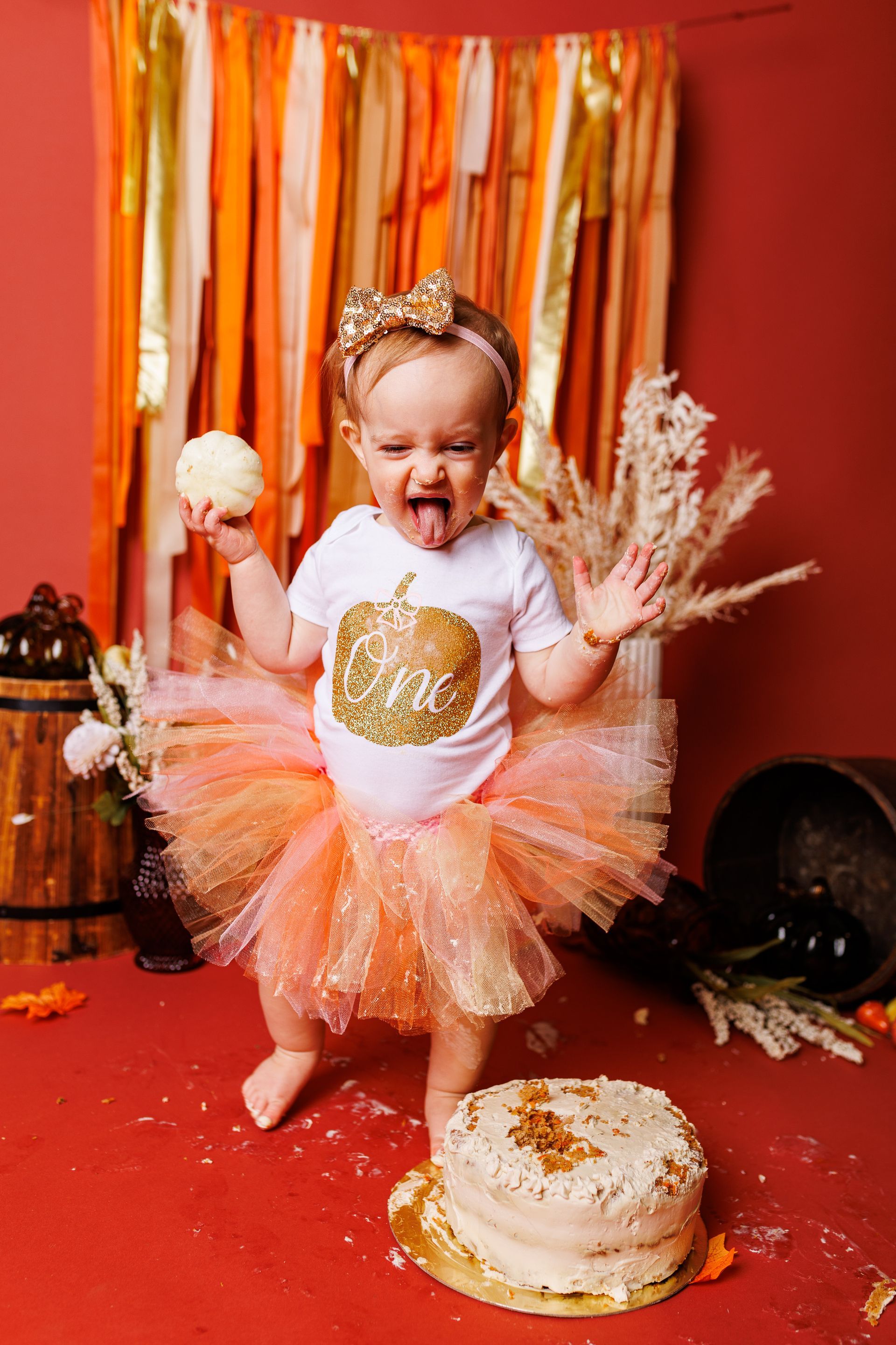 A little girl in a tutu is standing next to a cake.