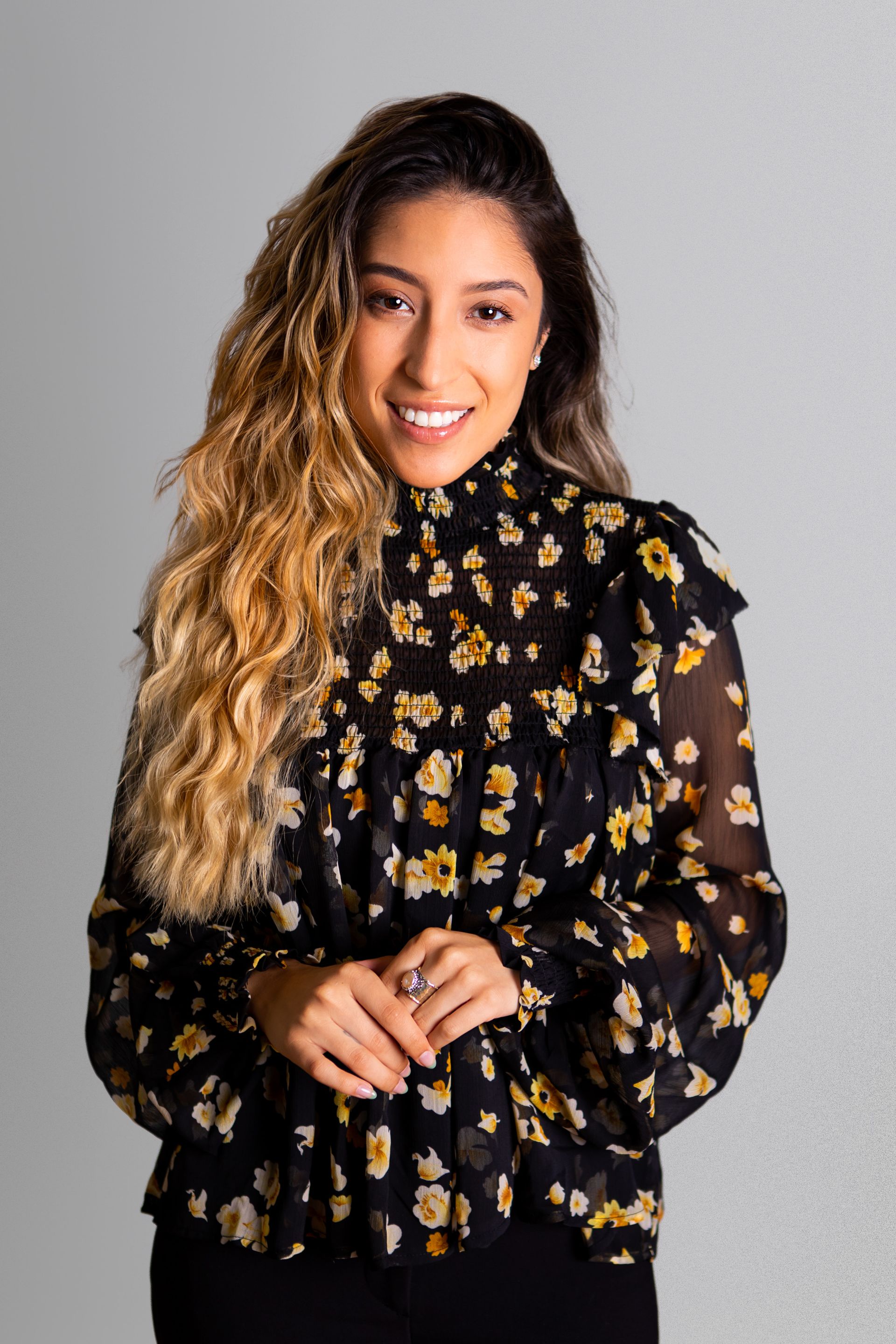 Photography MA -A woman is wearing a black floral blouse and smiling.