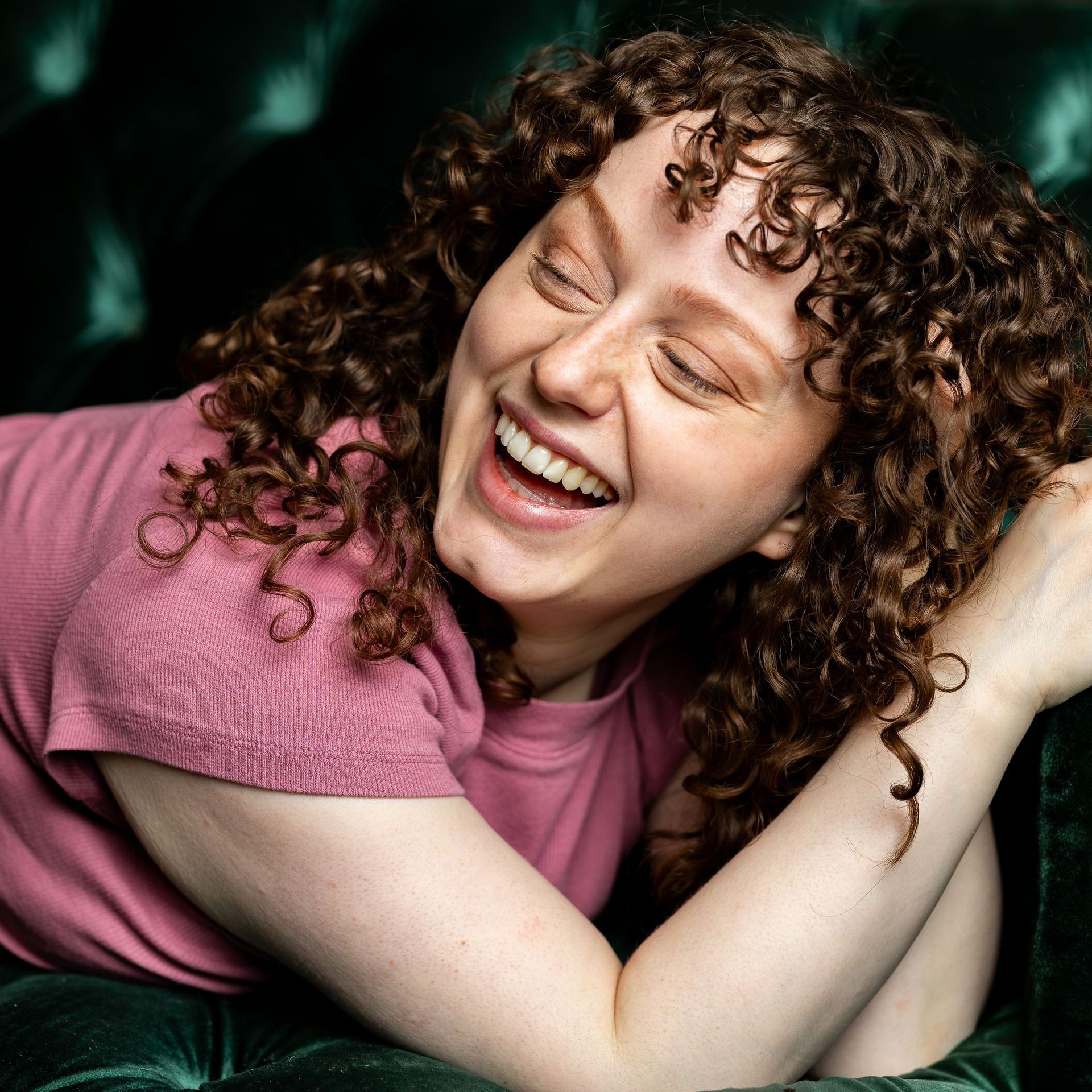 Photography MA -A woman with curly hair is laughing with her eyes closed