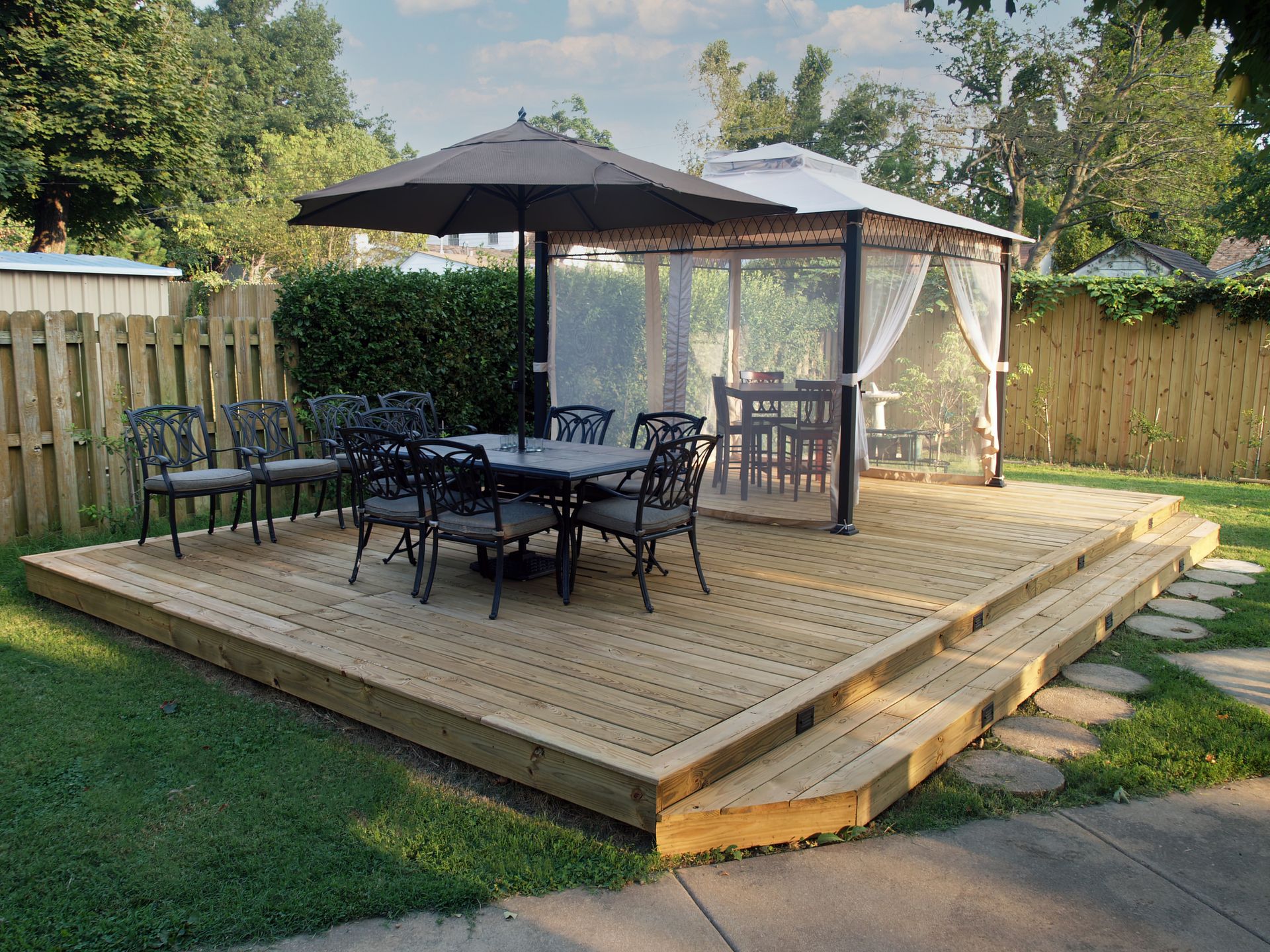 A wooden deck with a table and chairs under an umbrella.