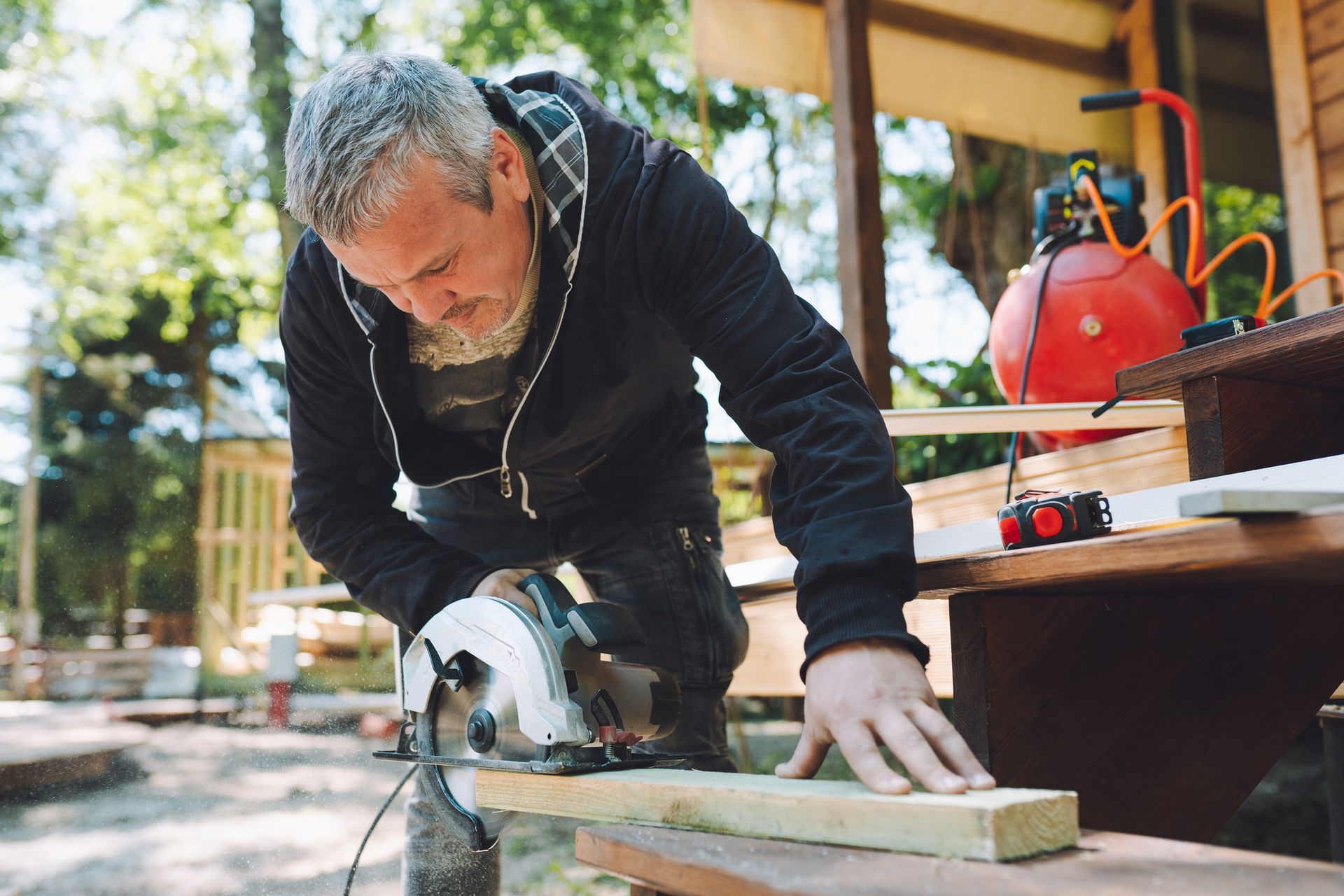 A man is using a circular saw to cut a piece of wood.