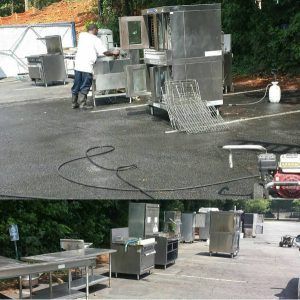 Outdoor industrial area with stainless steel equipment, carts, hoses, and a person in a white coat working nearby