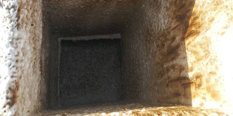 Dark rectangular tunnel opening in a rough stone wall, lit by sunlight on the right side.