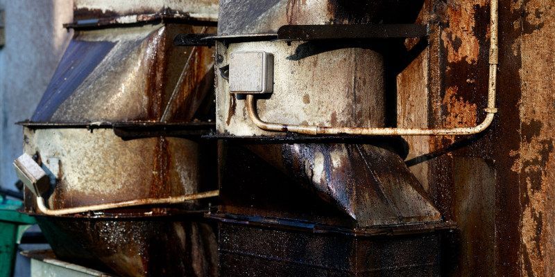 Rusty industrial machinery with metal pipes and worn blue panels close-up