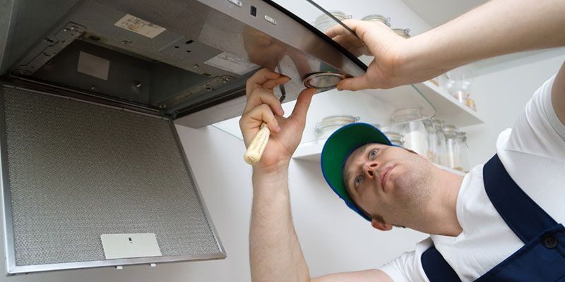 Technician inspecting a ceiling vent and ductwork inside a building
