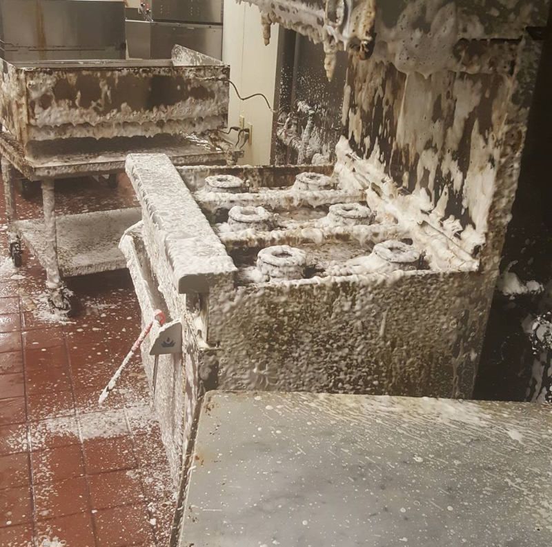 Snow-covered industrial machinery in a cluttered room with white residue on the floor and surfaces