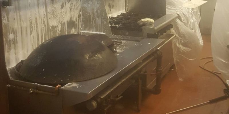 Black dome-shaped object on a metal table in a workshop, with hoses and equipment nearby.
