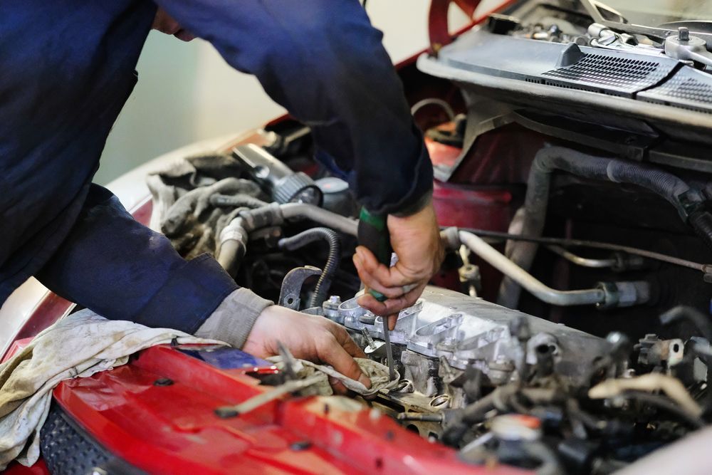 Mechanic Working on a Car Engine With a Screwdriver — B&D Auto Group & Towing in Bowen, QLD