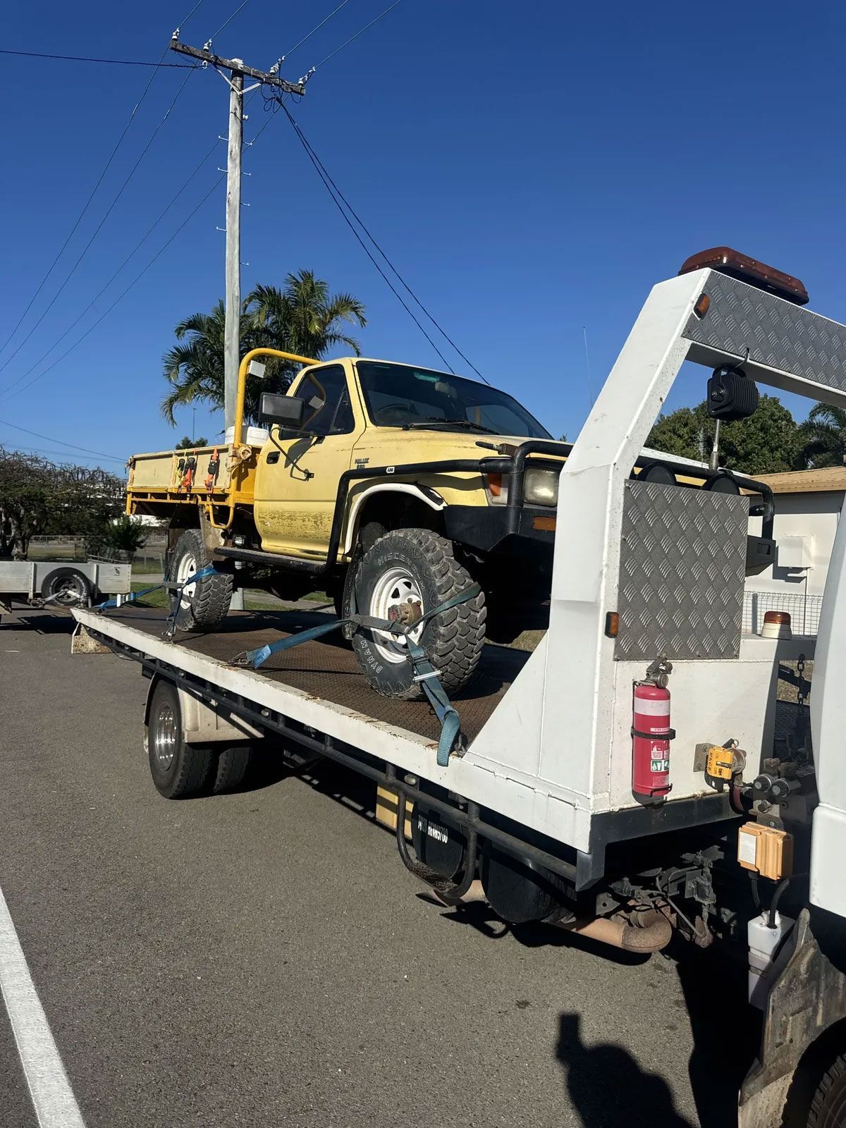 Yellow Truck on a Tow Truck, Parked on Pavement With a Phone Number Displayed — B&D Auto Group & Towing in Bowen, QLD