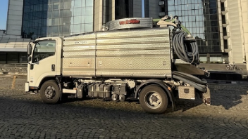 Un camioncino bianco parcheggiato su una strada acciottolata accanto a edifici moderni.