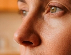 Close-up do olho e nariz de uma pessoa sob luz quente, olhando para a esquerda.