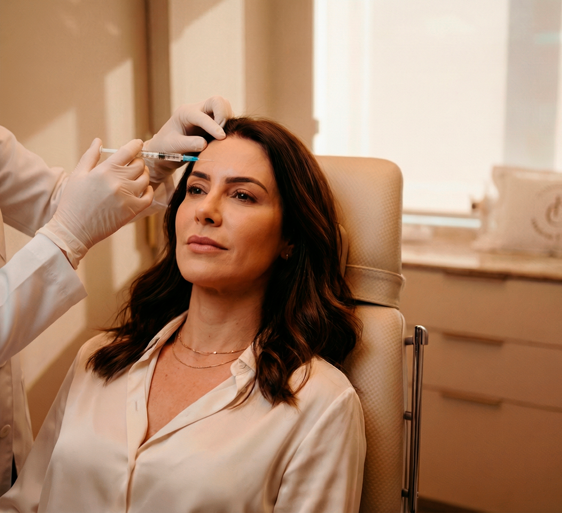 Mulher recebendo uma injeção estética de botox em um consultório bem iluminado.