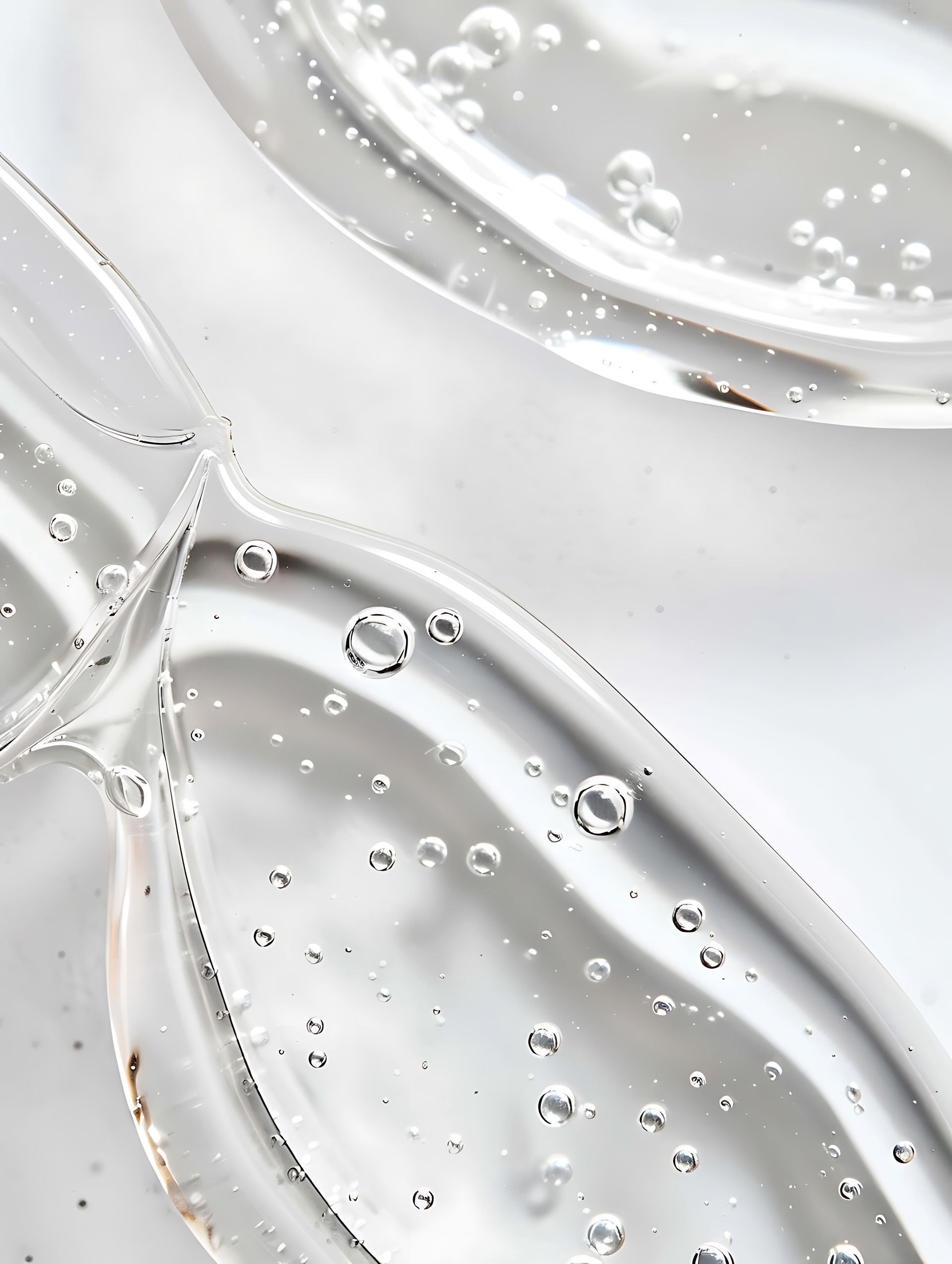 Gotículas de líquido transparente sobre uma superfície de vidro branco com curvas e reflexos abstratos.
