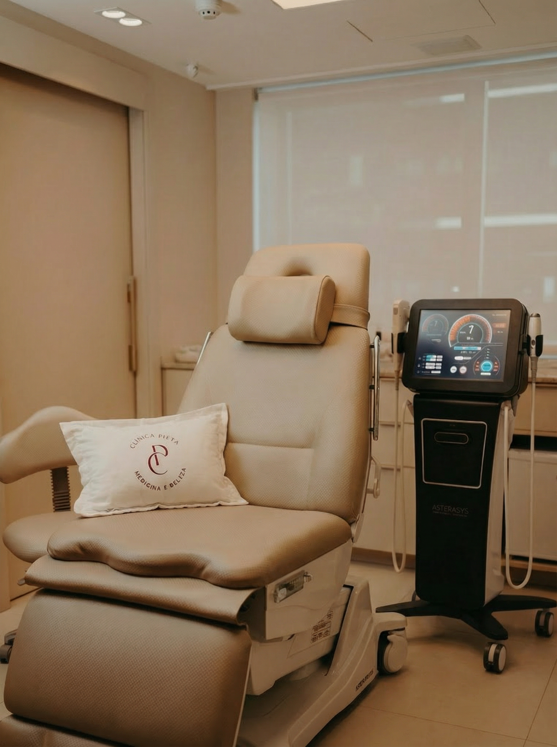 Poltrona de massagem bege em uma sala de clínica ao lado de um console de controle com tela sensível ao toque.