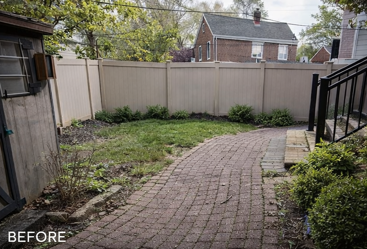 Before photo of a small backyard with a brick path, patchy grass, wooden fence, and shrubs