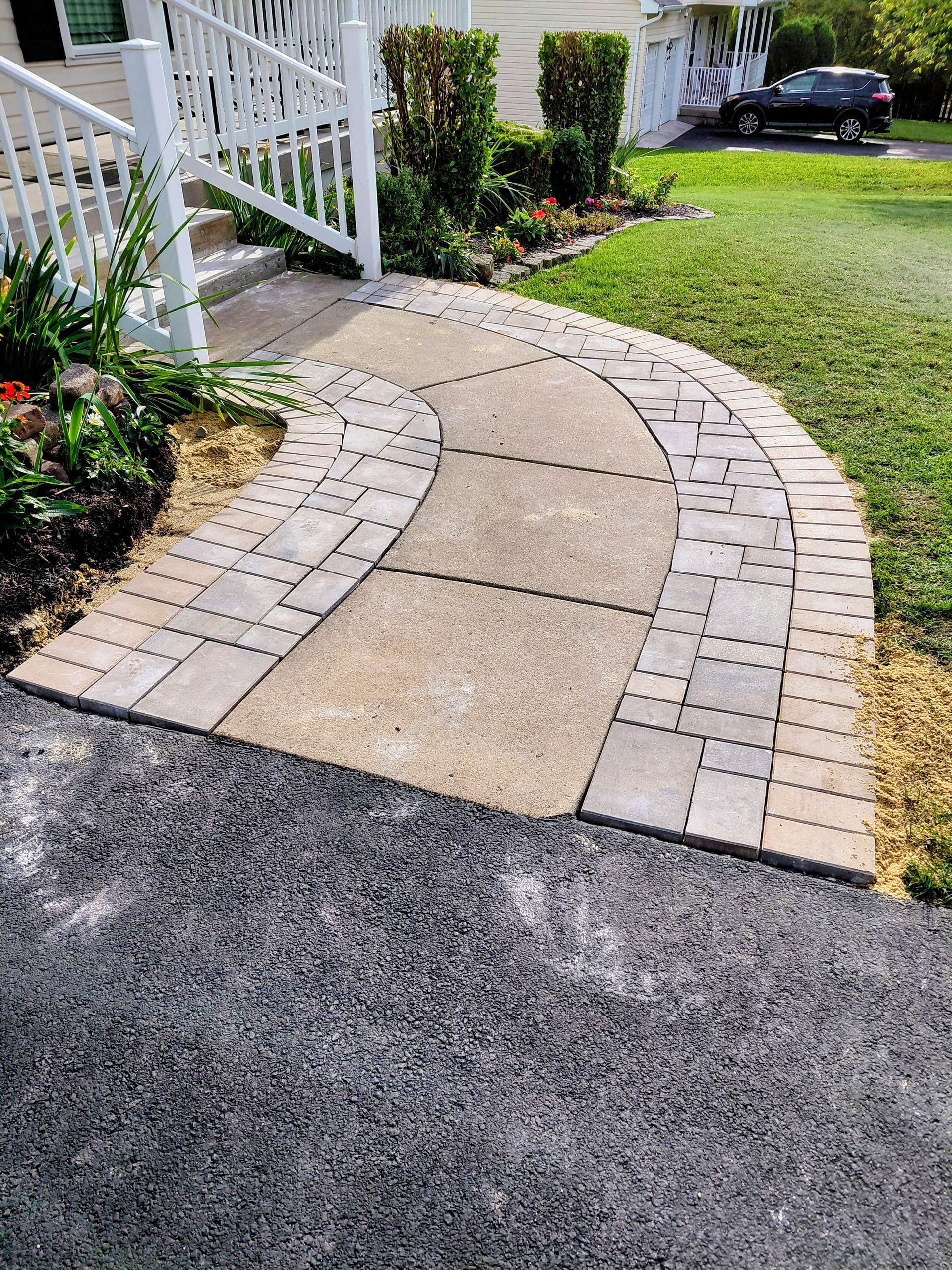 Modern bluestone patio with fire pit, seating, steps, and shrubs beside a house