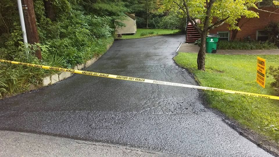 Freshly paved asphalt driveway with caution tape.