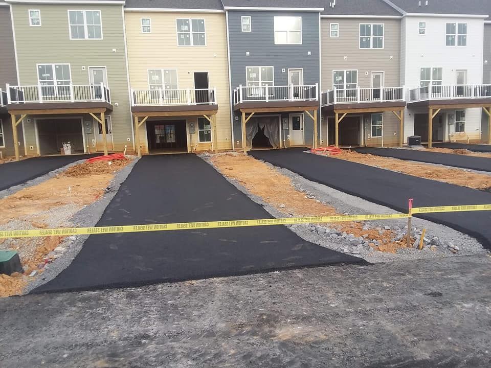 Row of townhouses with freshly paved driveways, construction debris, and caution tape.