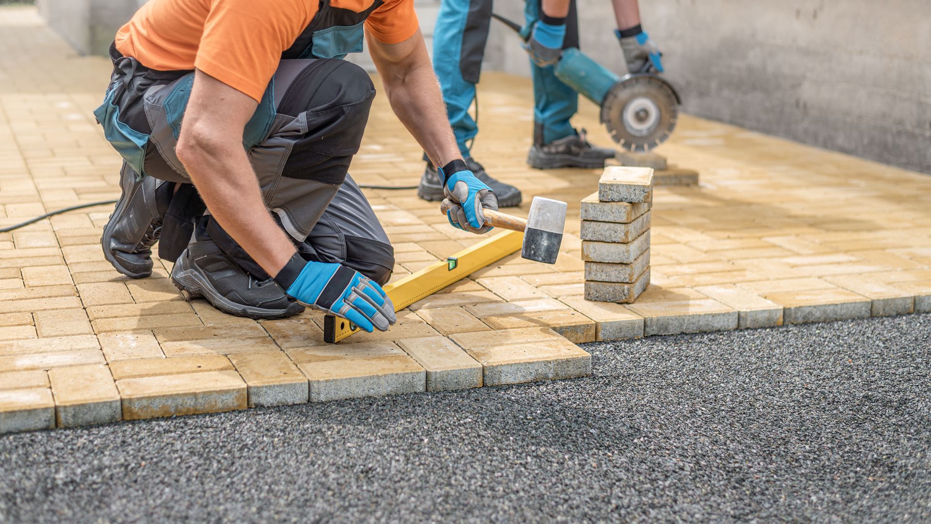 A man lays paving slabs and repairs a road.