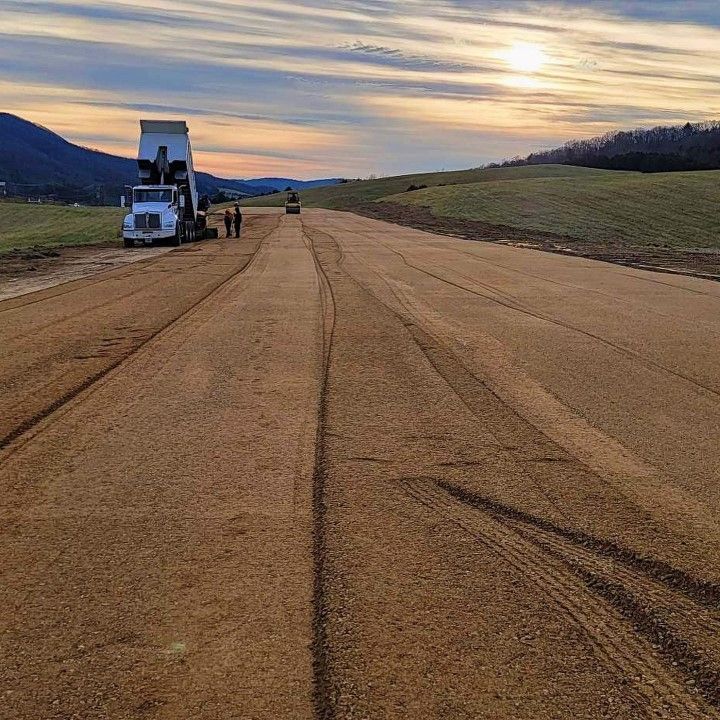 Truck dumping material on a construction site. Mountains and sunset in the background.