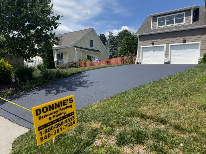 Asphalt driveway sealed by Donnie's, leading to a two-car garage. Houses in background.