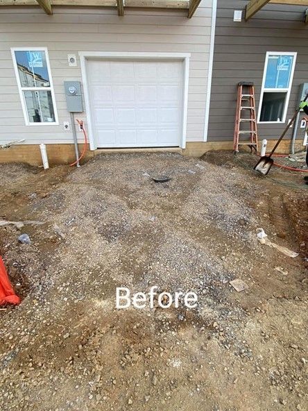 Construction site before concrete. Garage door and building backdrop, with gravel and dirt ground.