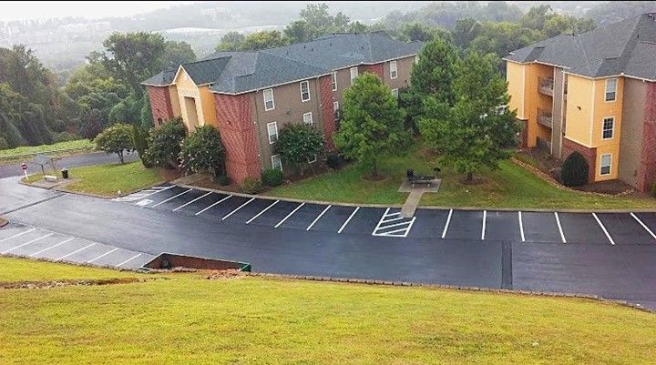 Apartment buildings with a parking lot on a hillside, overcast day.
