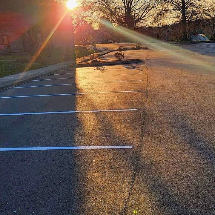 Golden sunlight over empty asphalt parking lot with white lines.