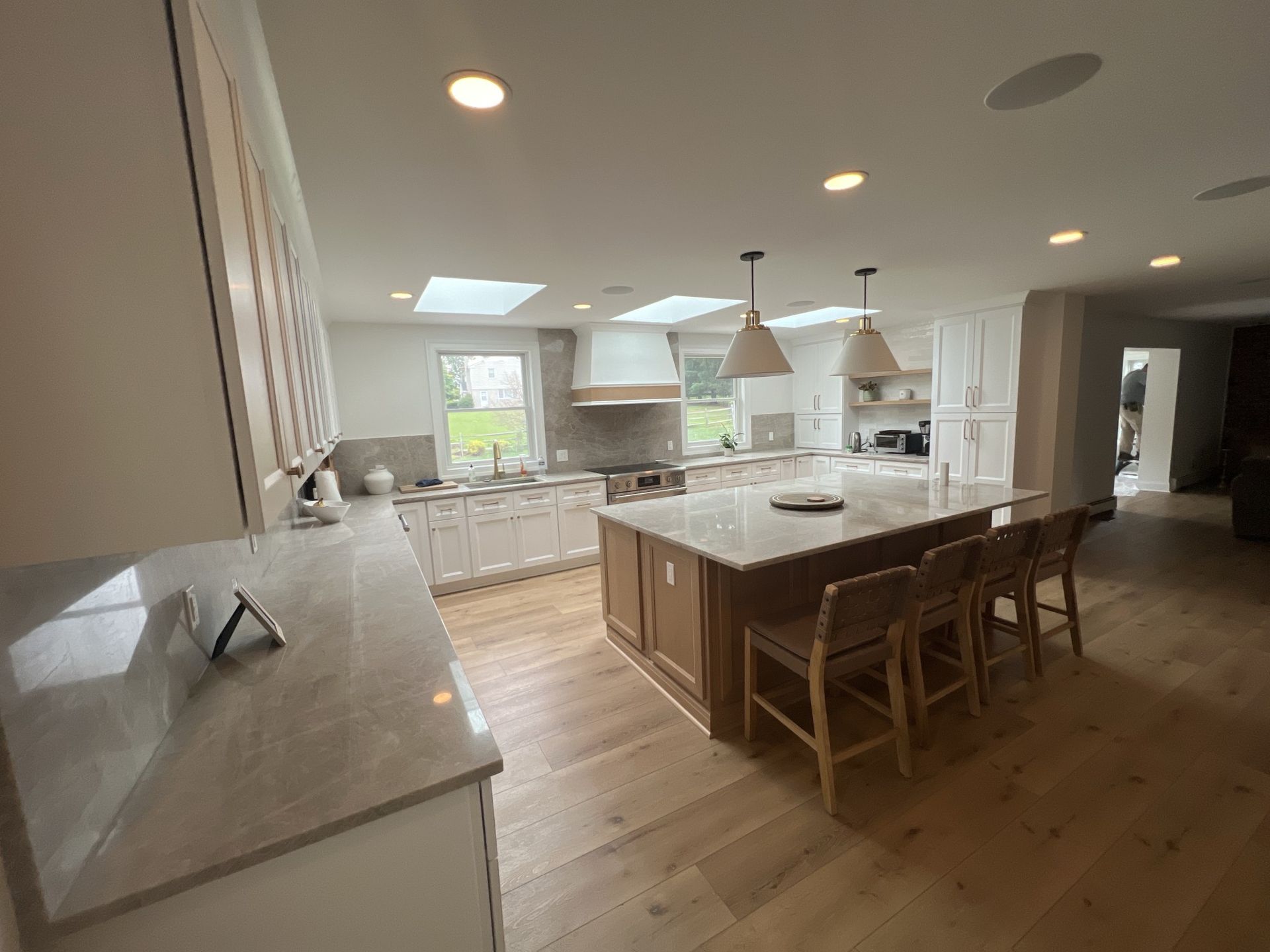 Spacious kitchen with a large island, wooden floors, skylights, and white cabinets.