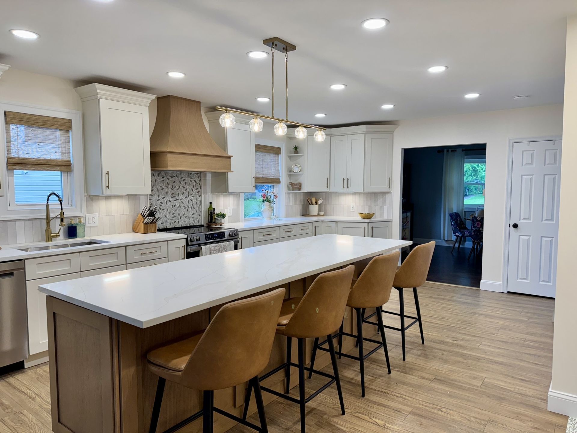 Modern kitchen with island, beige and white cabinets, tan bar stools, and hardwood floors.