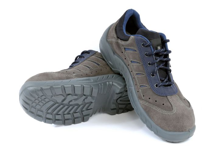 Un paio di scarpe da lavoro stringate in camoscio grigio con dettagli blu scuro e suola spessa in gomma 