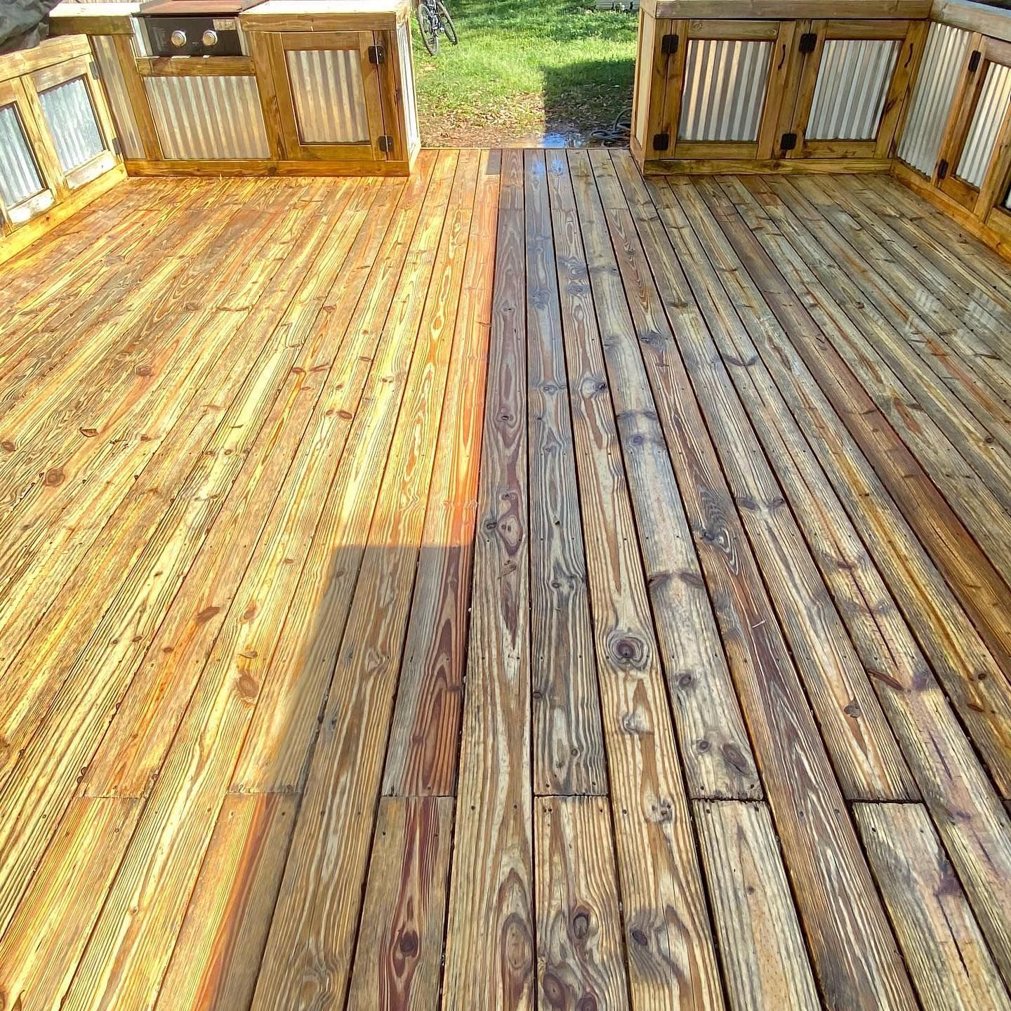 Wooden deck, half stained, half unstained. Outdoor setting with two corrugated metal and wood cabinets.