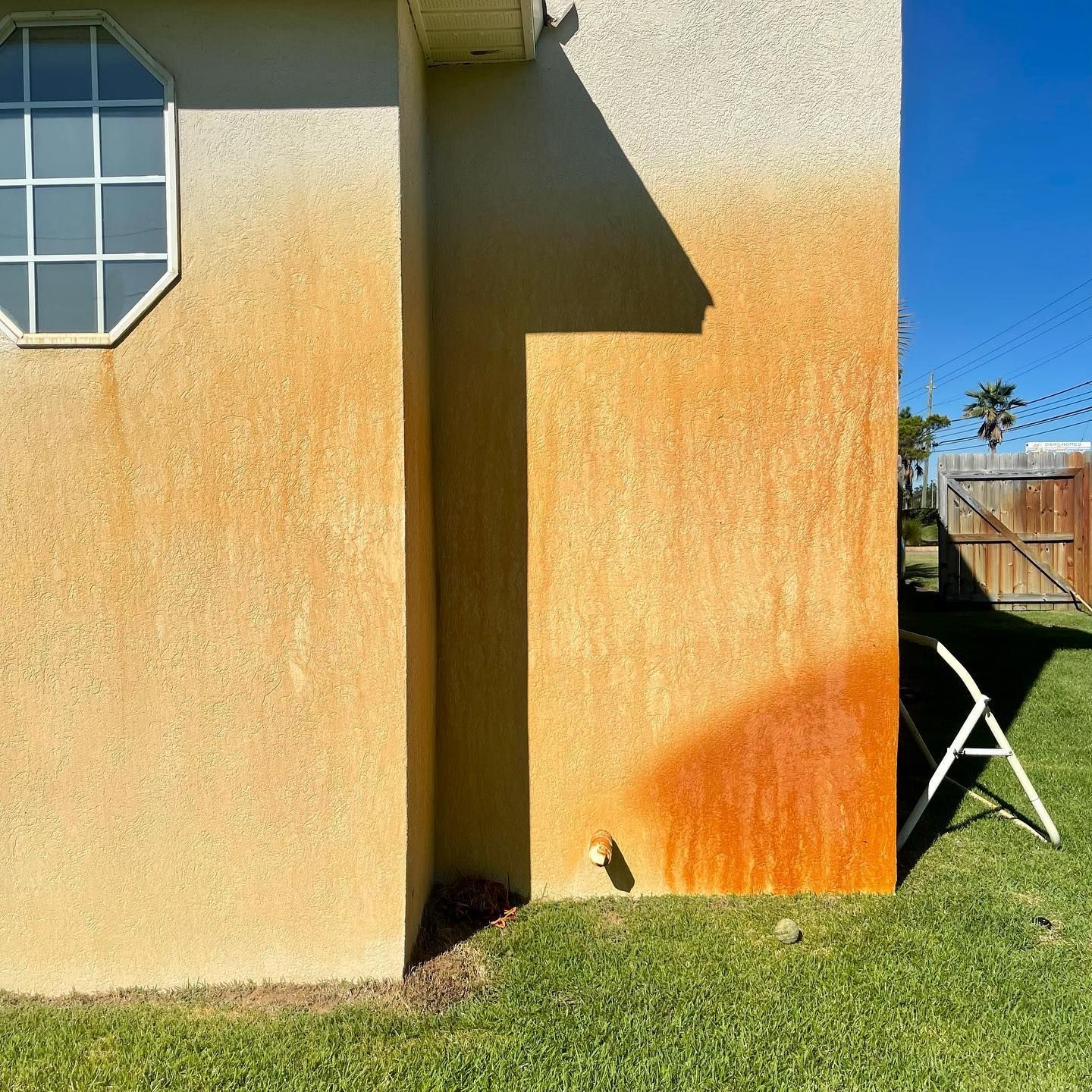 Orange stained stucco wall on a house with a shadow cast on it.