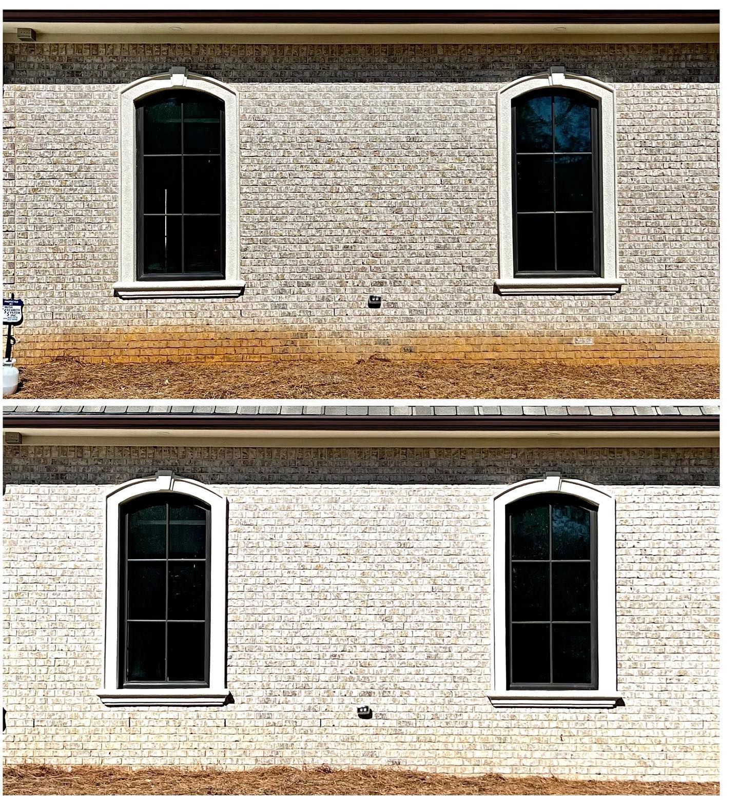 Four arched-top, black-framed windows on a brick building with tan trim.