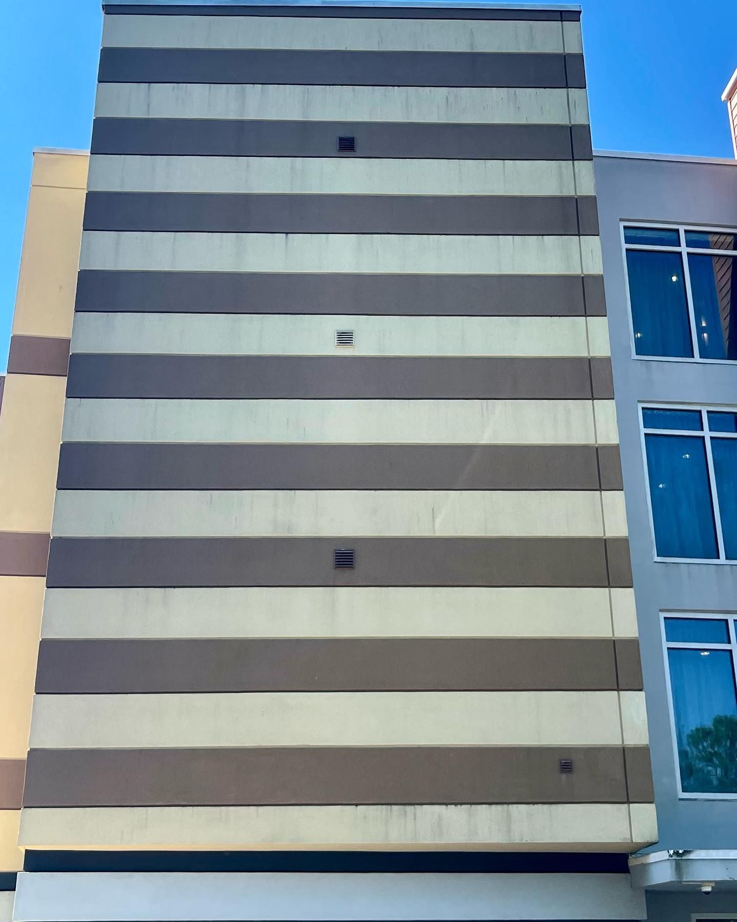 Striped building facade with alternating beige and brown bands. Blue sky visible.