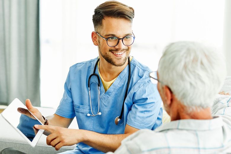Doctor in blue scrubs talking with a patient during a consultation in a bright clinic office
