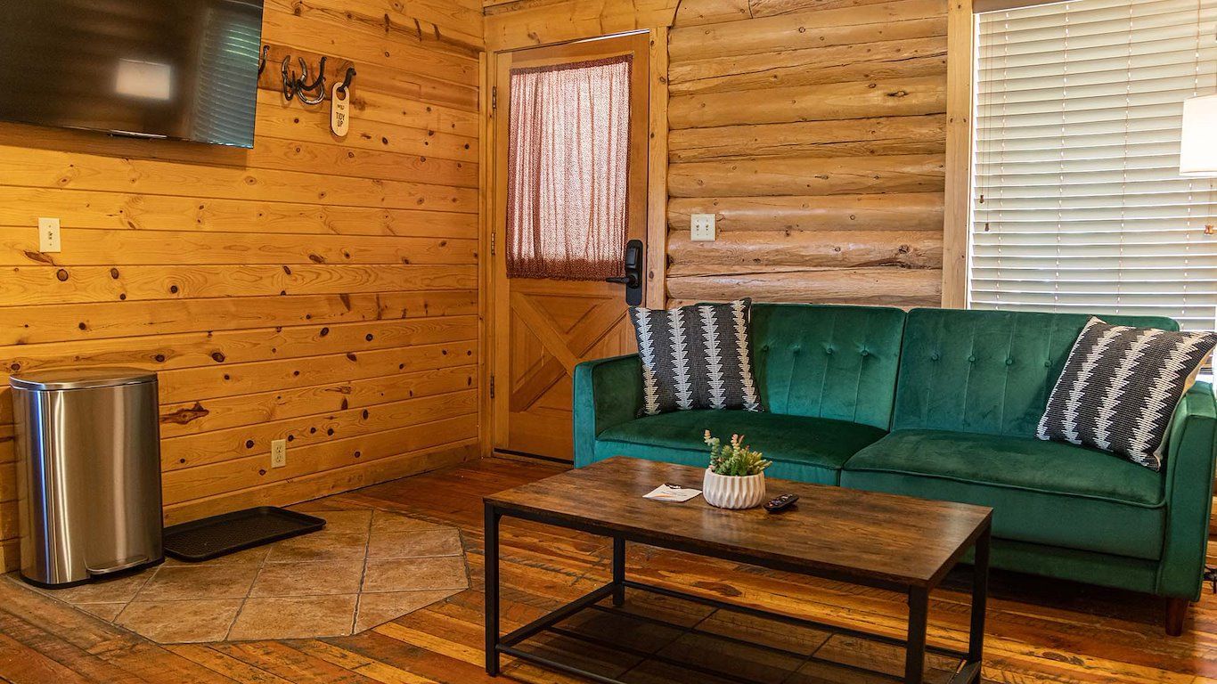Cozy living room with green sofa, wooden walls, coffee table, and TV.