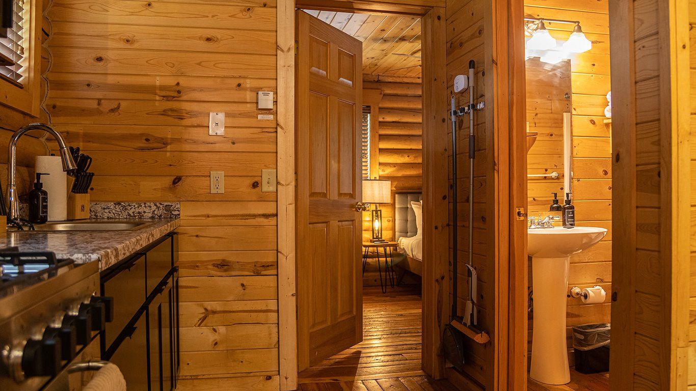 Interior view of a cabin with kitchen on the left, doorway to a bathroom on the right, and hallway in between.
