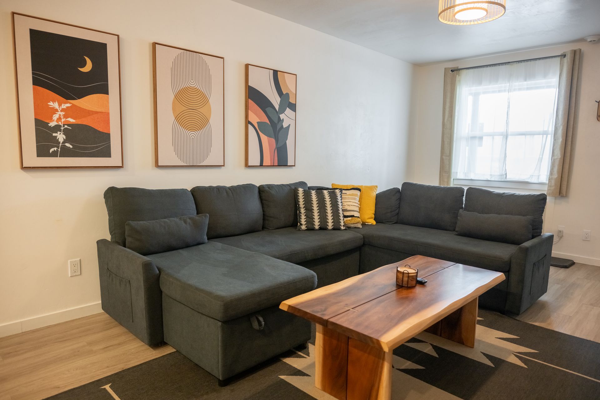 Cozy living room with a gray sectional sofa, wooden coffee table, and wall art.