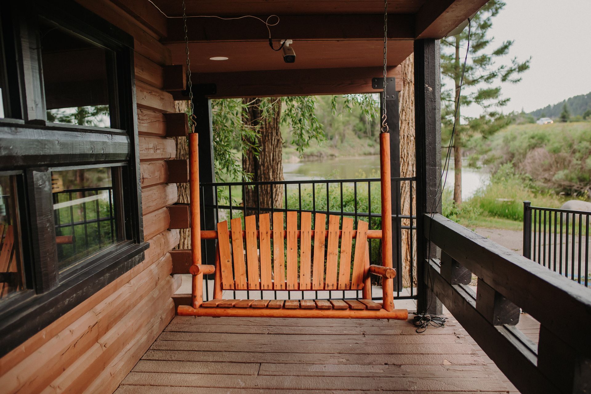 Wooden porch swing on a cabin porch overlooking a river.