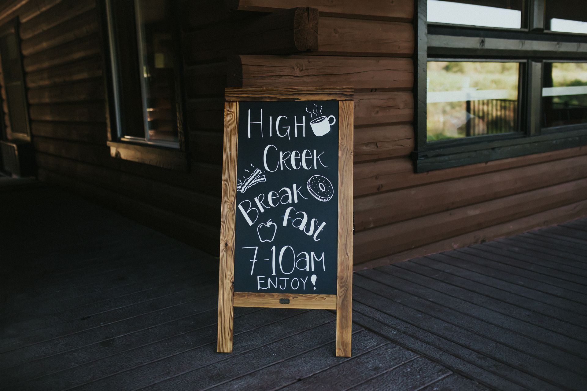 A wooden sign outside a cabin advertises High Creek breakfast from 7-10 am.