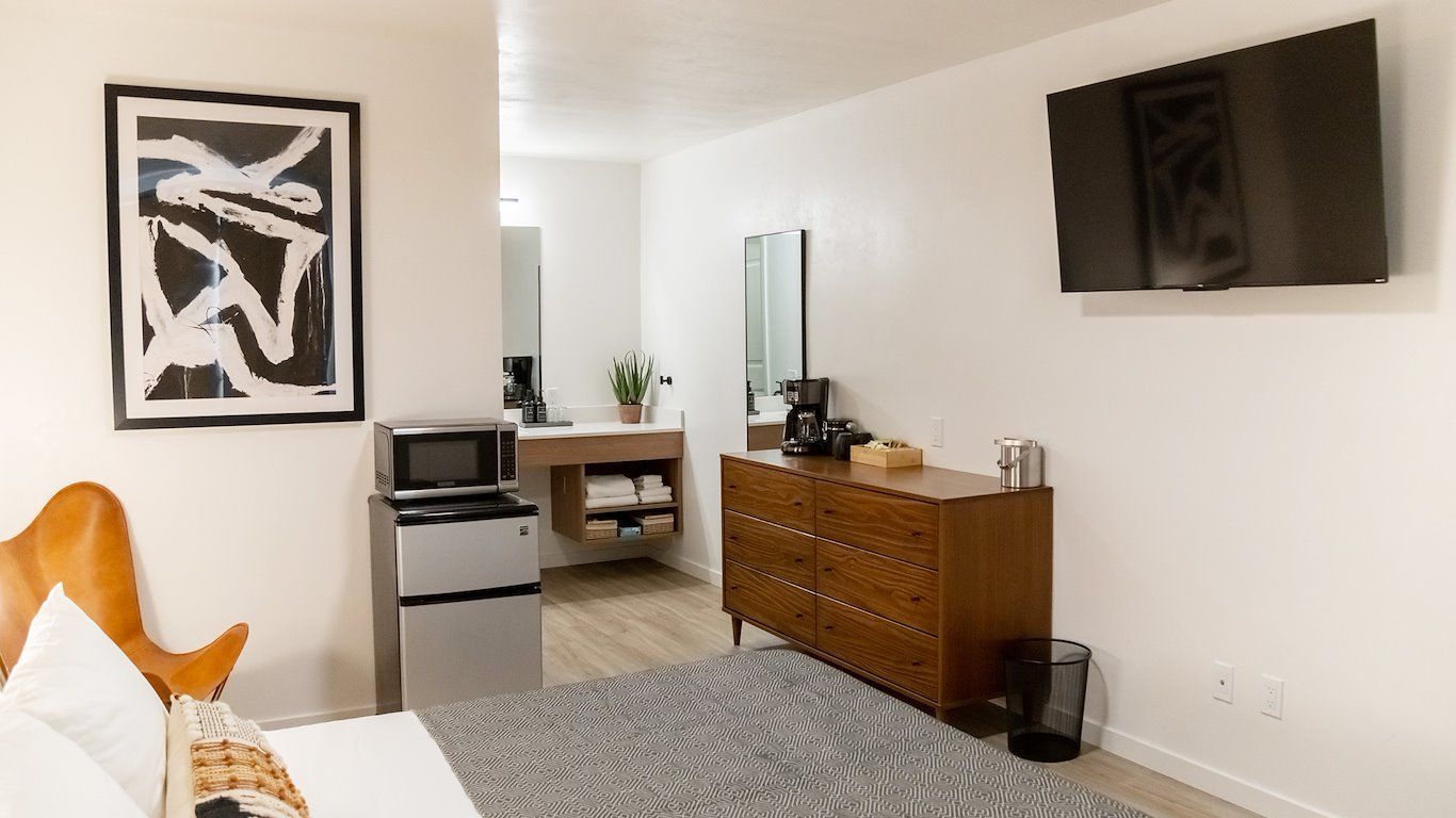Hotel room with a bed, dresser, TV, microwave, and bathroom in the background.