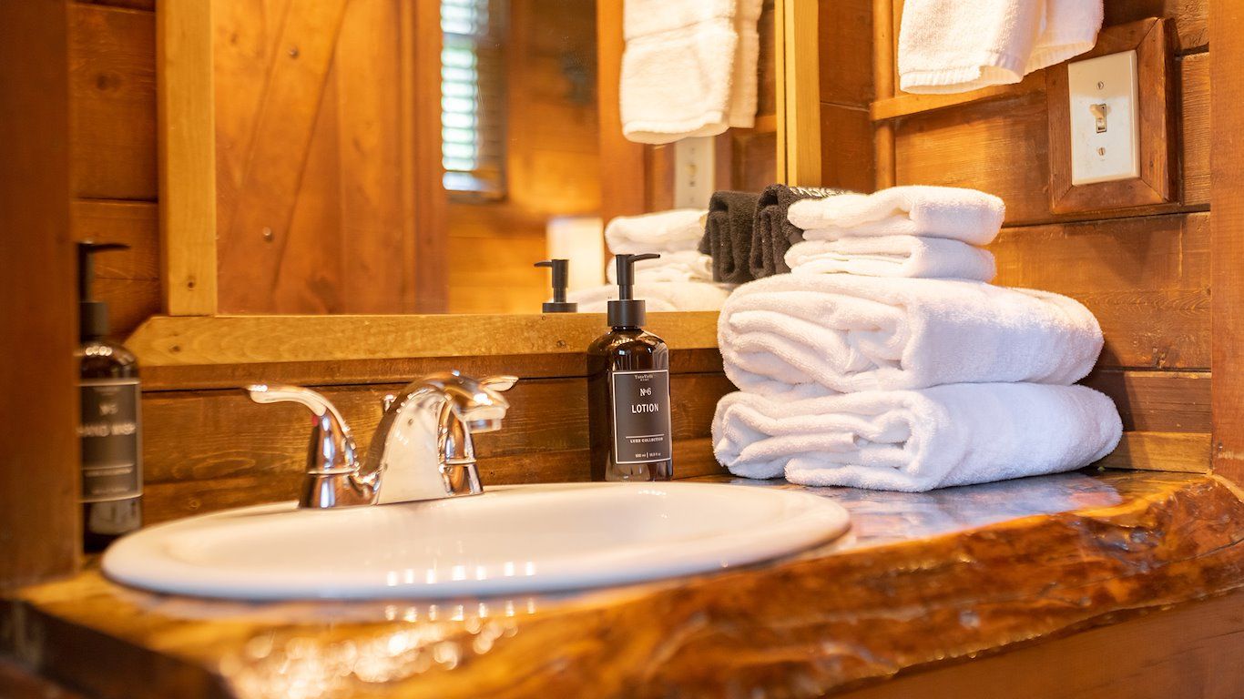 Bathroom with a sink, towels, and mirror, all set in a wooden cabin style with natural wood accents.
