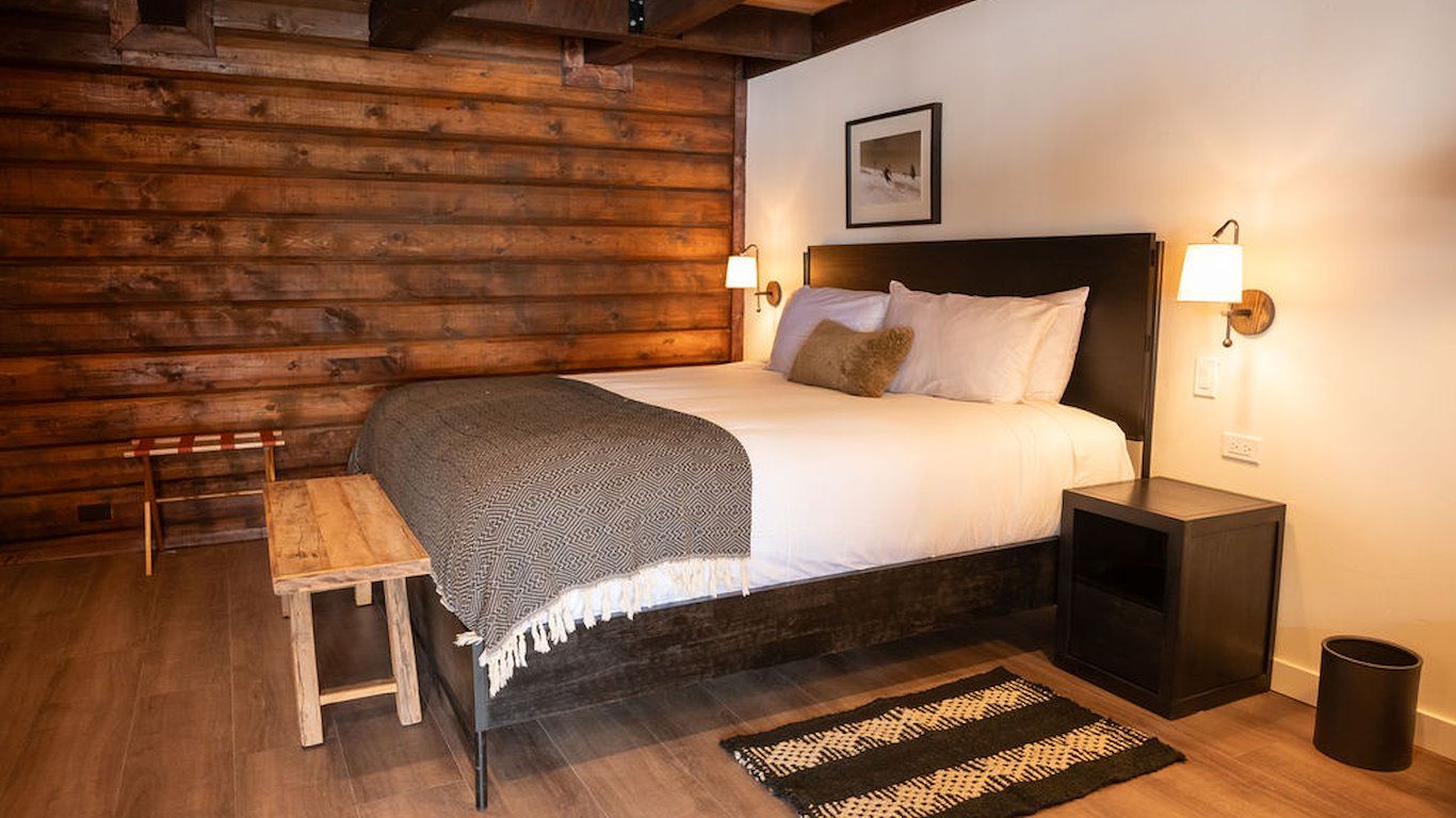Cozy bedroom with a bed, wooden bench, and log wall.