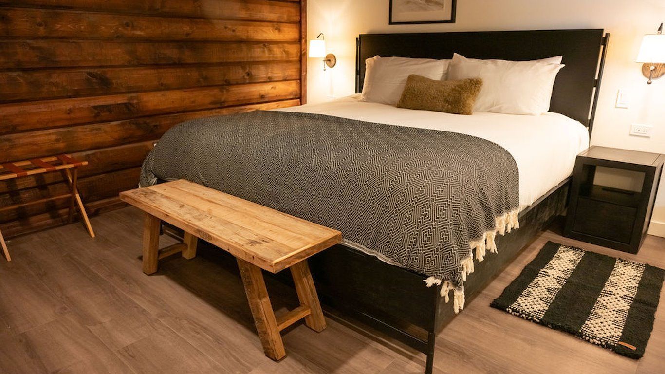 Bedroom with a bed, wooden bench, and wooden wall.