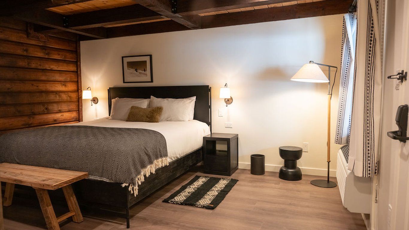 Bedroom with a bed, wooden bench, log walls, and a standing lamp.