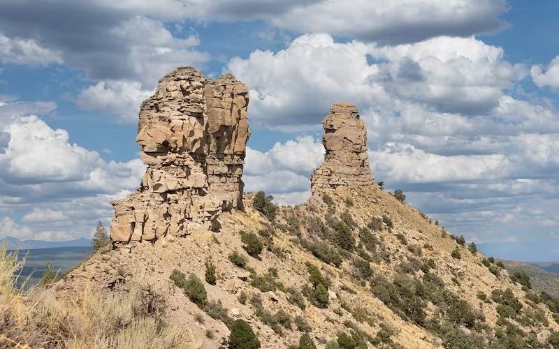Two eroded rock formations under a cloudy blue sky.